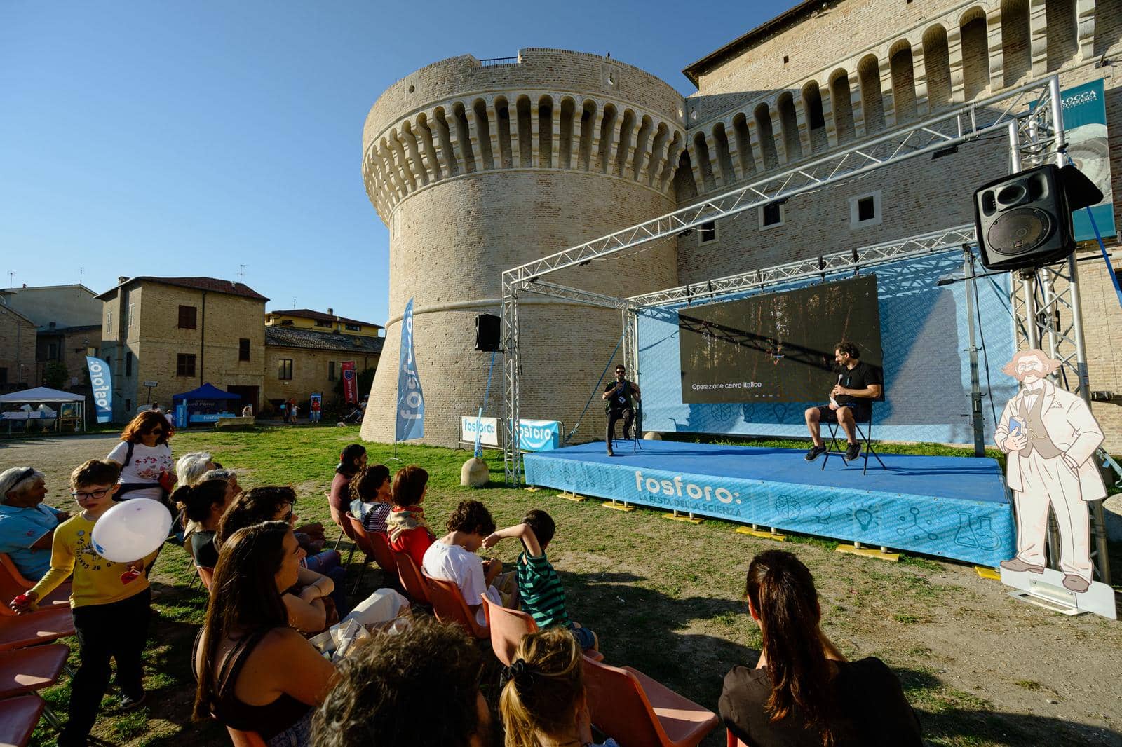 The audience seated in front of the stage at the foot of the Rocca Roveresca