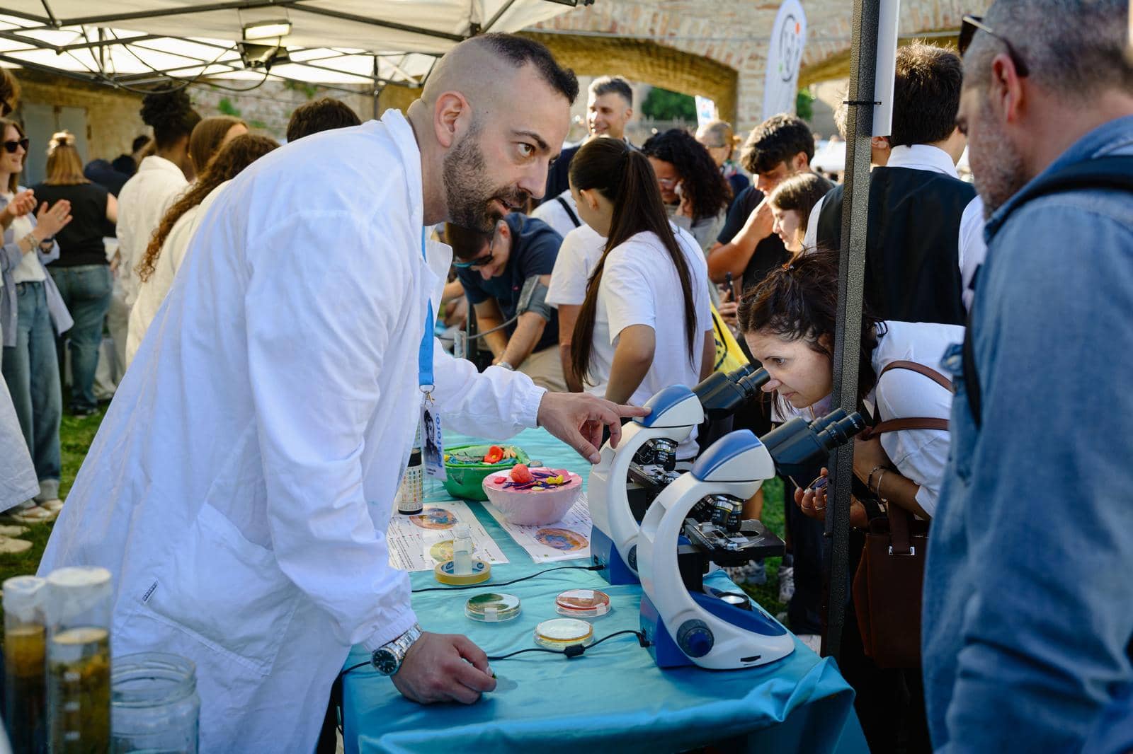 A visitor looking through a microscope at a researcher's stand