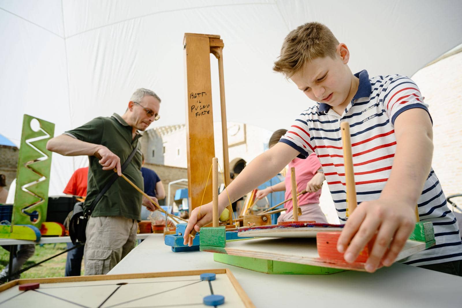 A child assembling a wooden exhibit during a workshop under the gazebo